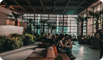 An indoor lounge with palms and people seated together