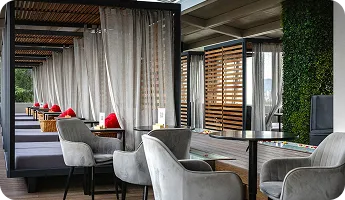 A rooftop lounge with sheer curtains and low seating
