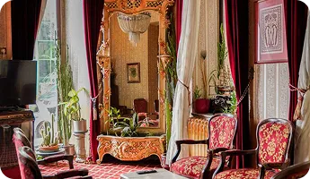 An opulent lounge with a gold mirror and red velvet chairs